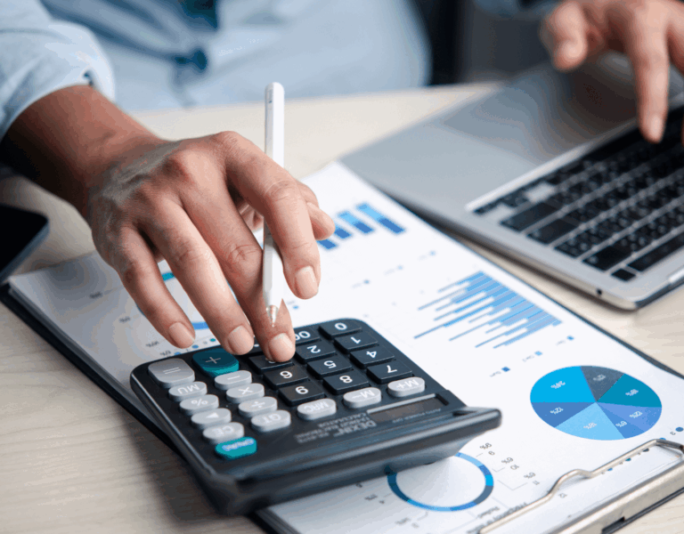 Image of a person using a calculator and reviewing business valuation charts and financial reports.