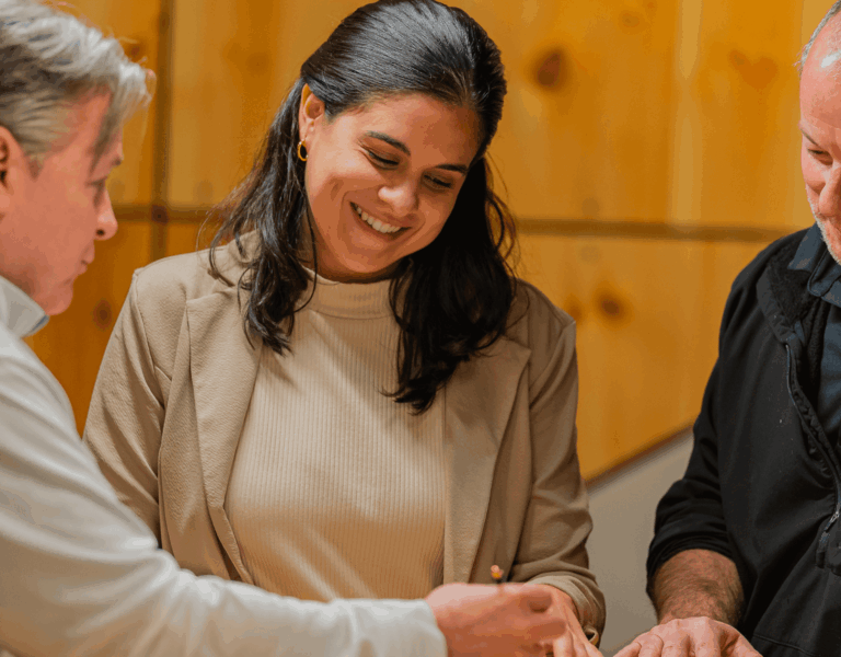 A business owner smiling while meeting with two business consultants during a confidential coaching session.